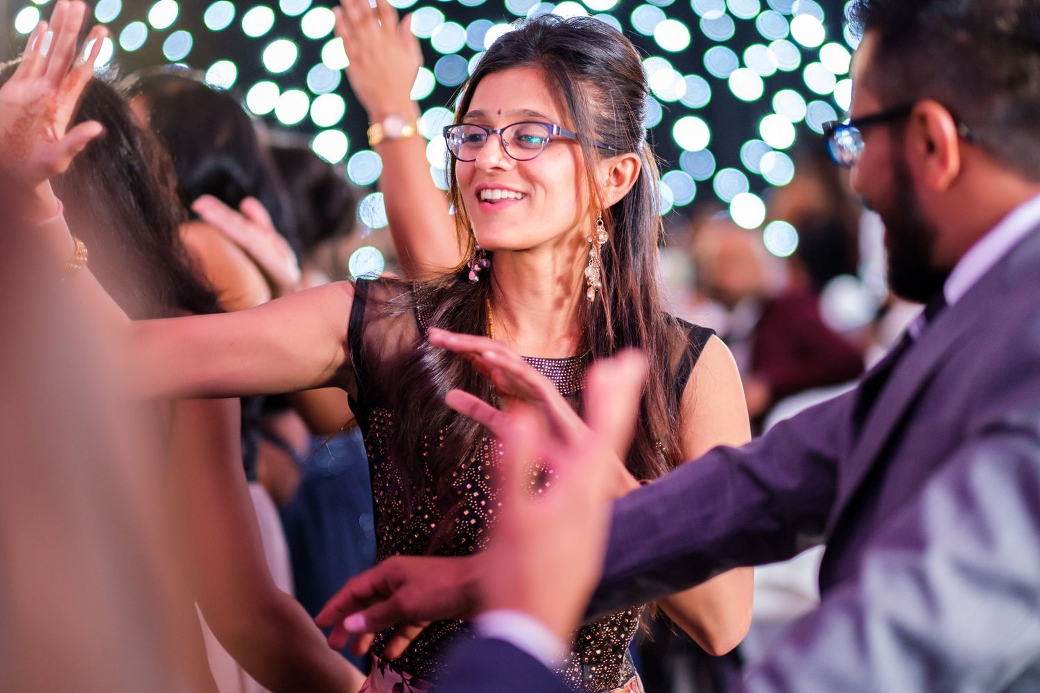People dancing with bokeh lights creating a festive atmosphere in the background.