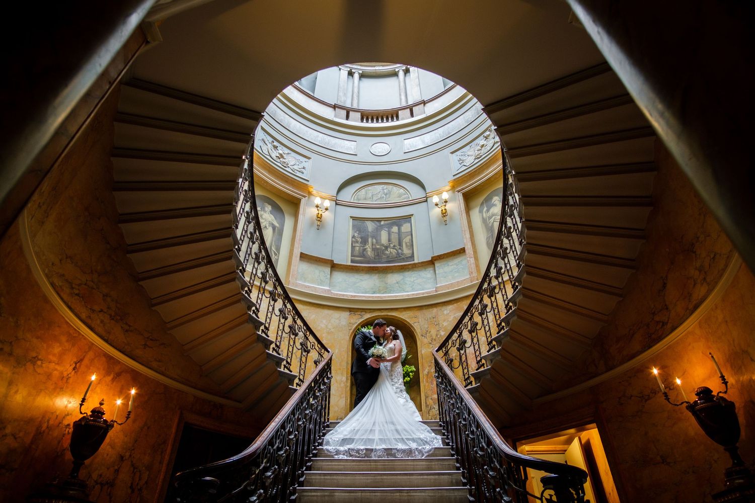 Looking up at ornate domed ceiling with circular skylight in historic building.