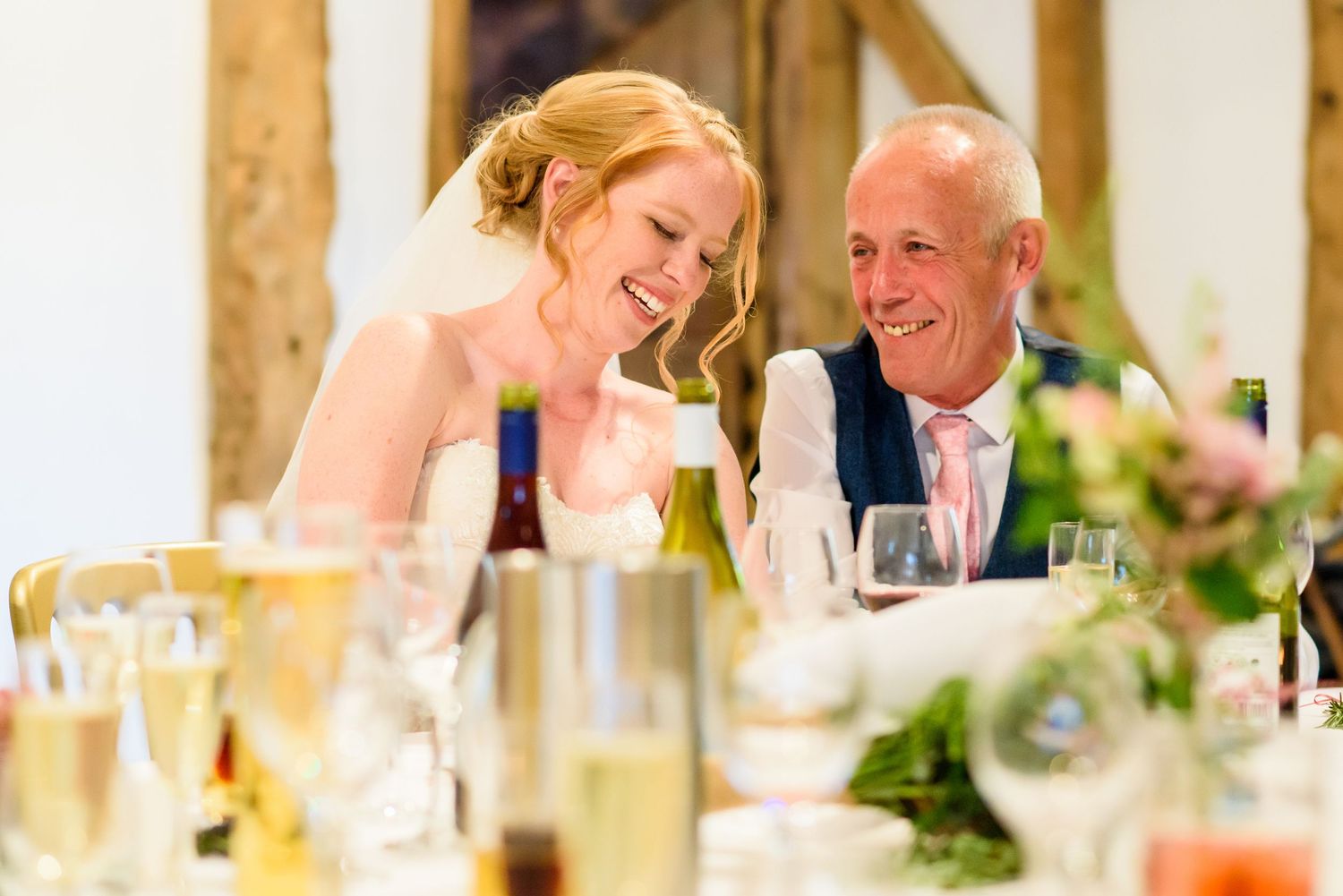 Wedding reception celebration with guests dining at rustic wooden tables.