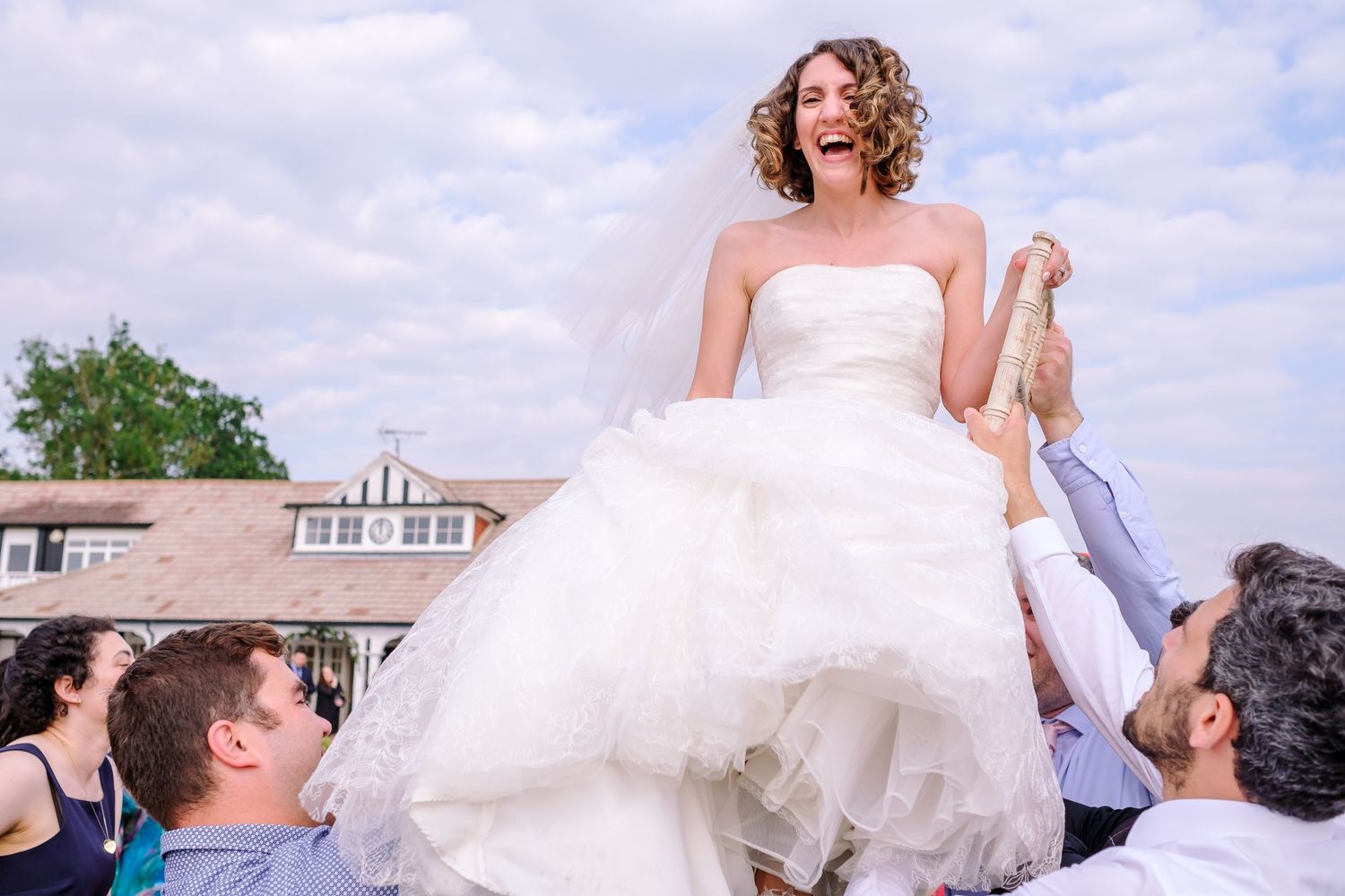 Celebration with people dancing outdoors on a sunny day with white dress flowing.