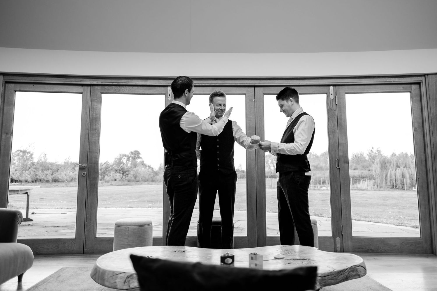 Black and white panoramic view of wedding party members gathered in modern venue space.