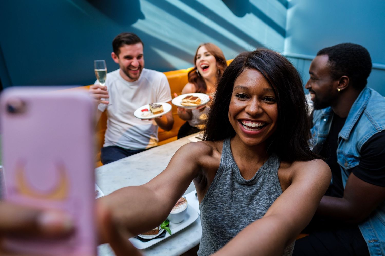 Group of friends taking selfies while enjoying pizza together.
