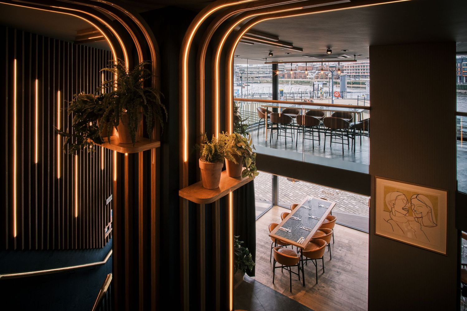 Modern restaurant interior with curved archways, ambient lighting and hanging plants.
