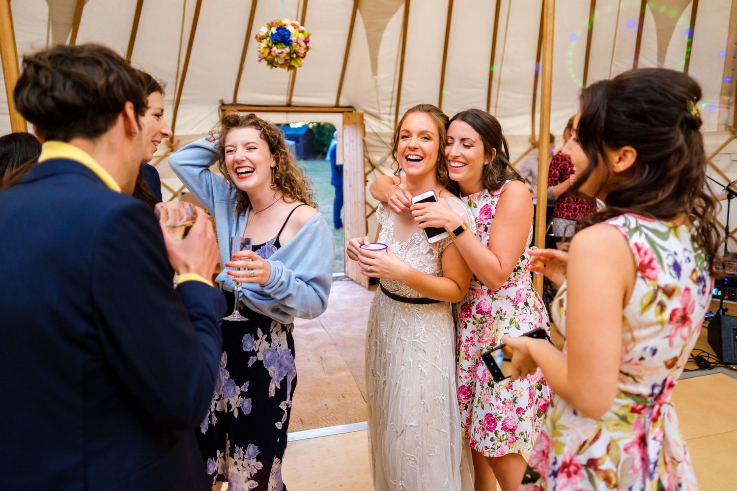 Wedding party dancing and celebrating in a rustic indoor venue with joyful expressions.