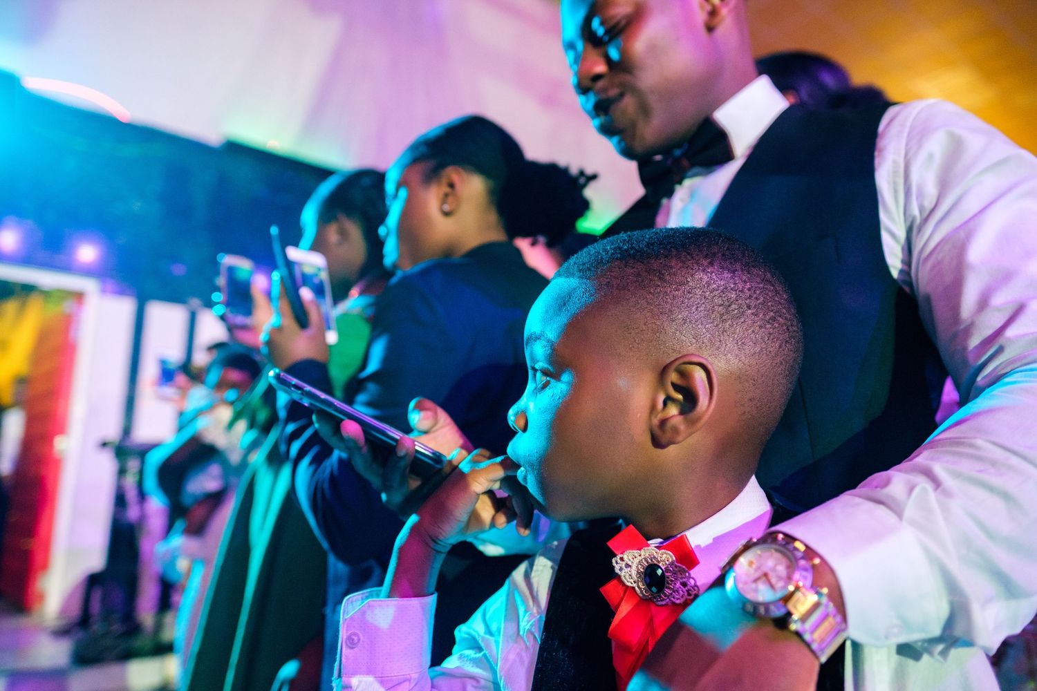 Wedding reception guests enjoying drinks and entertainment with colorful lighting.