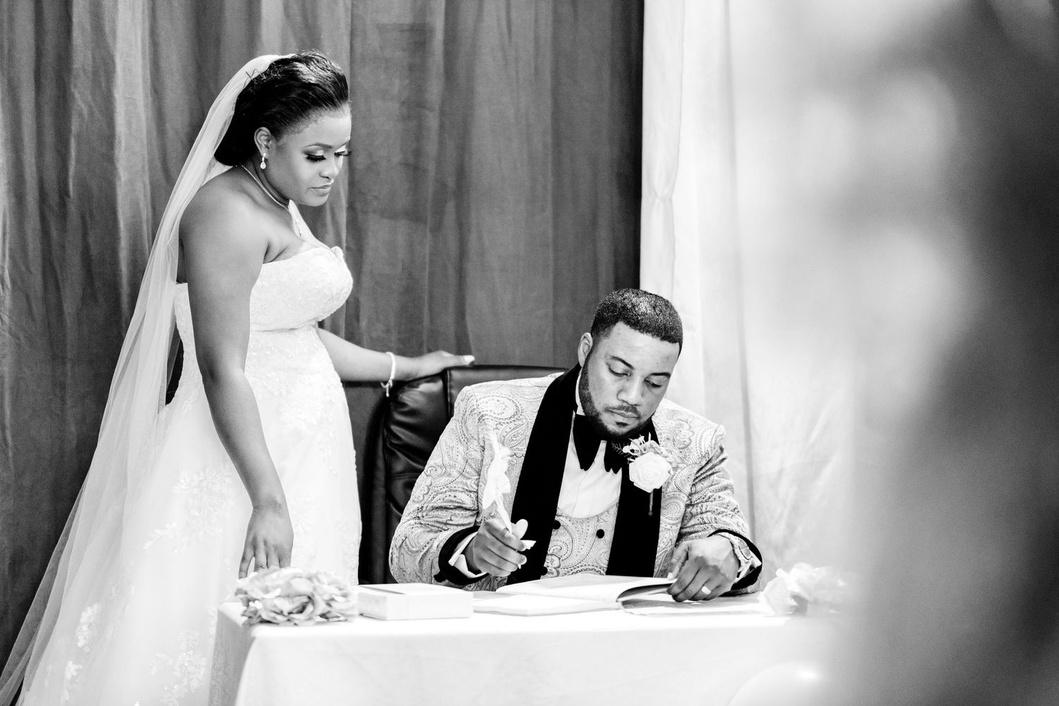 Black and white photo of wedding ceremony signing documents at altar.