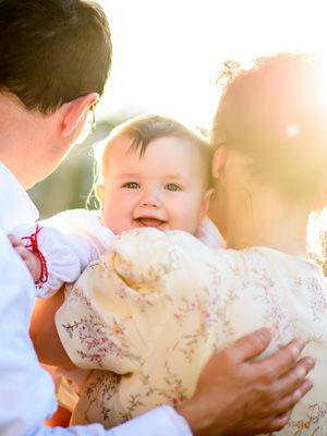 Tender family moment captured in sunlit outdoor setting.