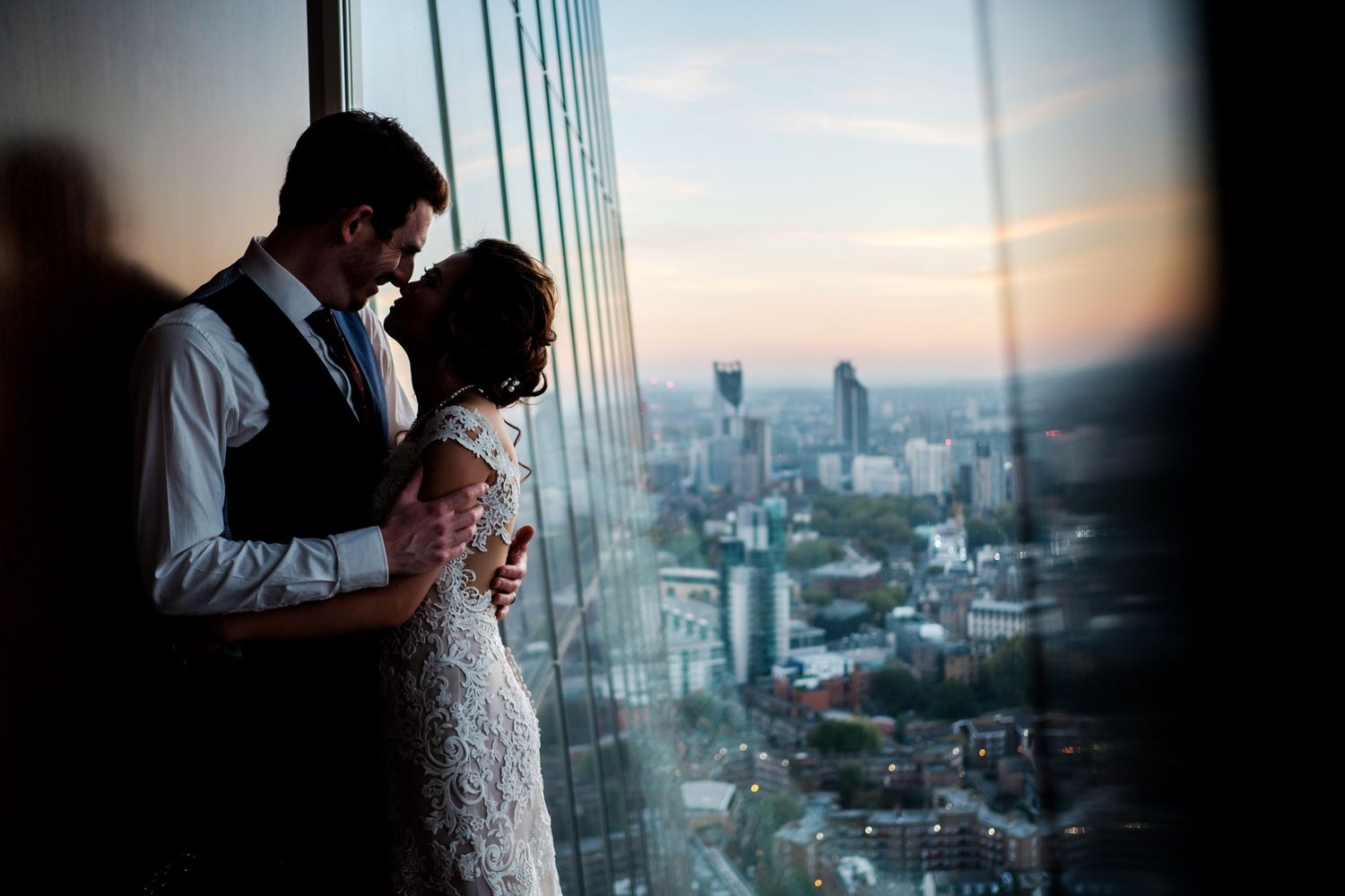 A romantic cityscape moment with a couple silhouetted against a window during sunset.