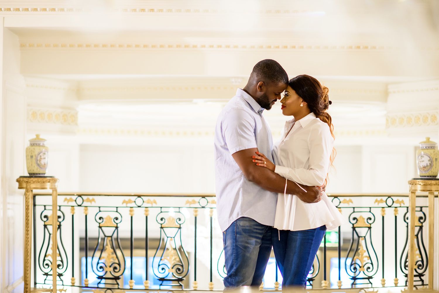 A couple embraces in a bright, modern space with decorative metal railings.