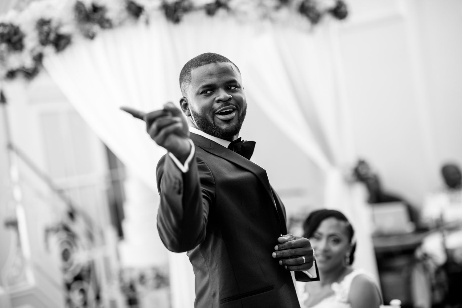 Black and white photo of a wedding guest gesturing enthusiastically during the celebration.