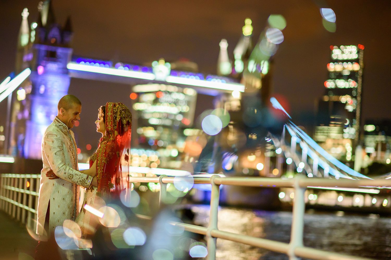 Tower Bridge glows with blue and white lights against the dark London skyline.