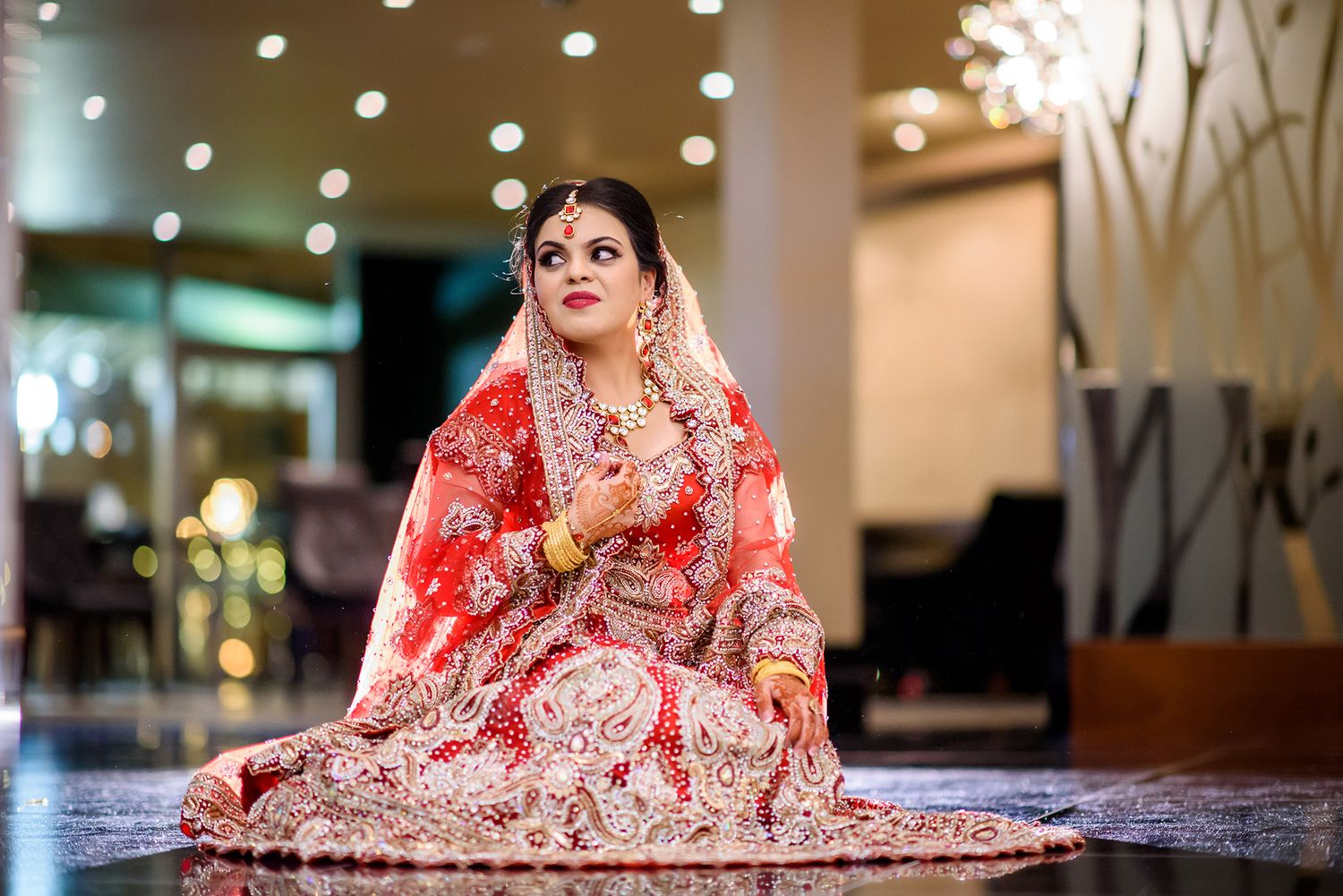 Beautiful red bridal lehenga with intricate embroidery captured in an elegant indoor setting.