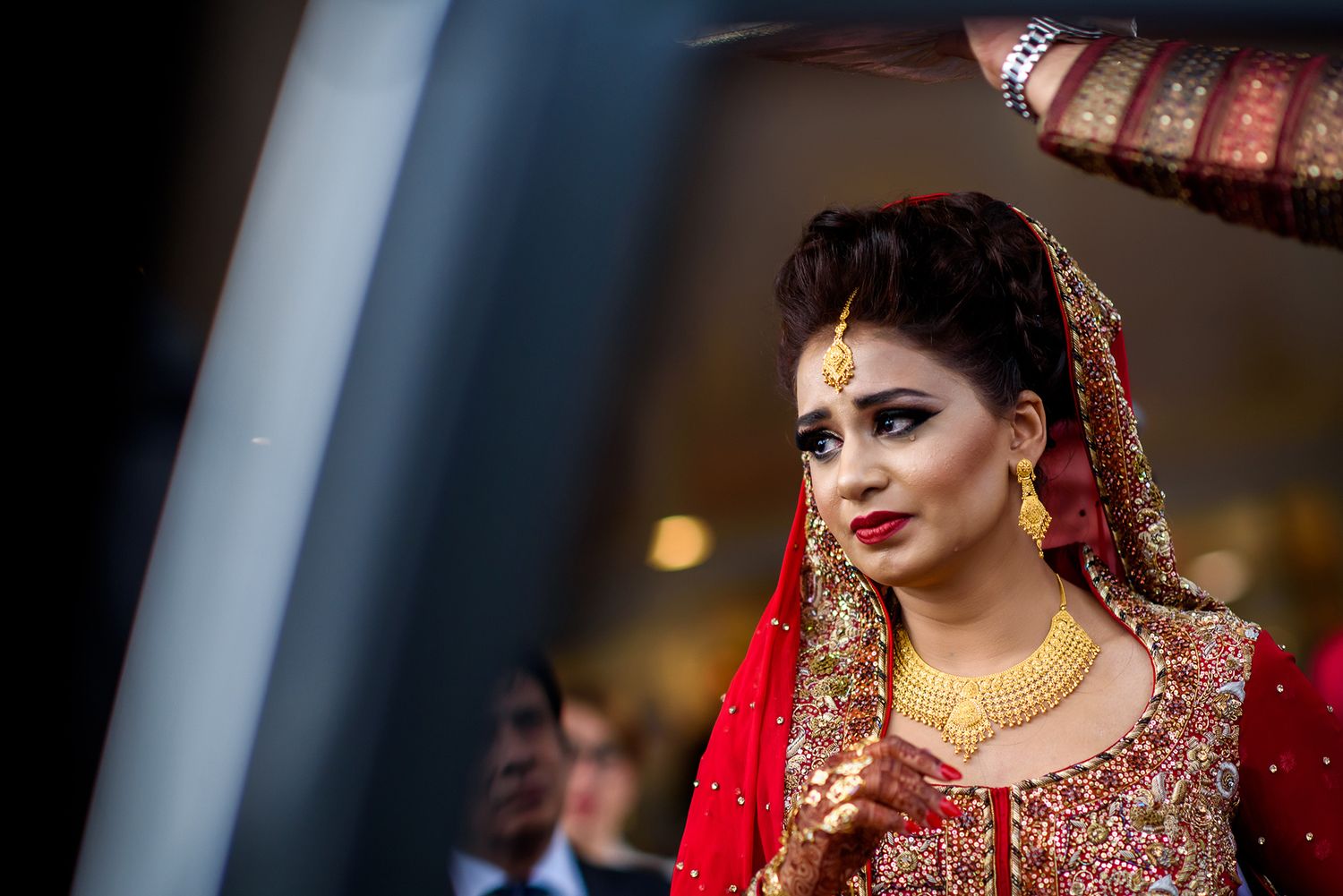 Candid shots of bride in red and gold traditional Indian wedding attire with elaborate makeup.