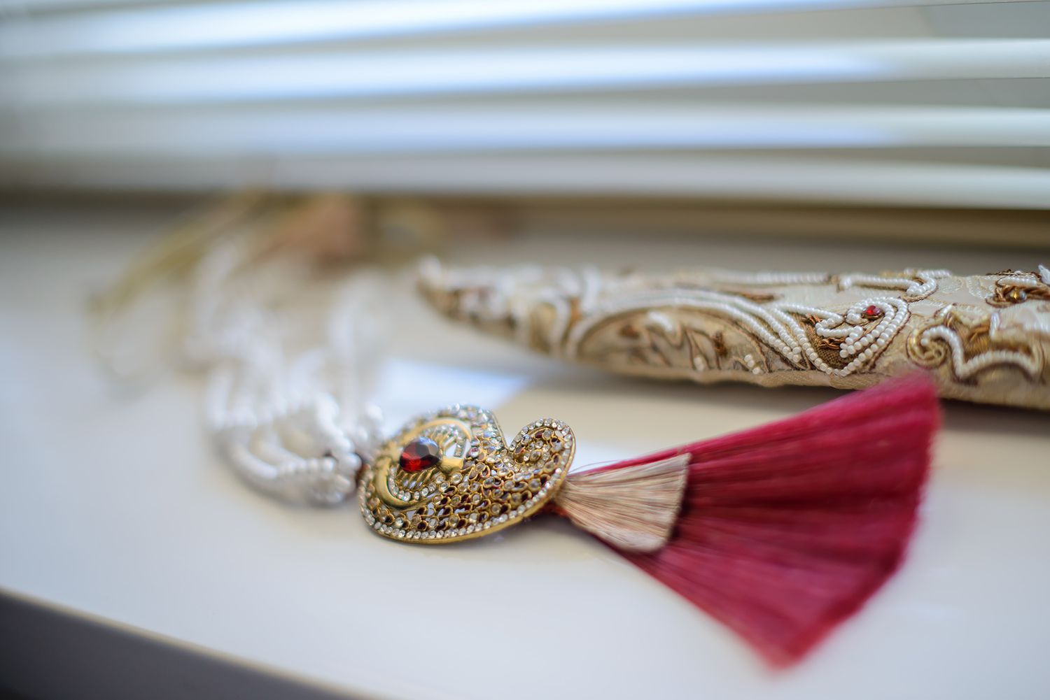 Elegant gold and burgundy wedding accessories displayed on white surface.