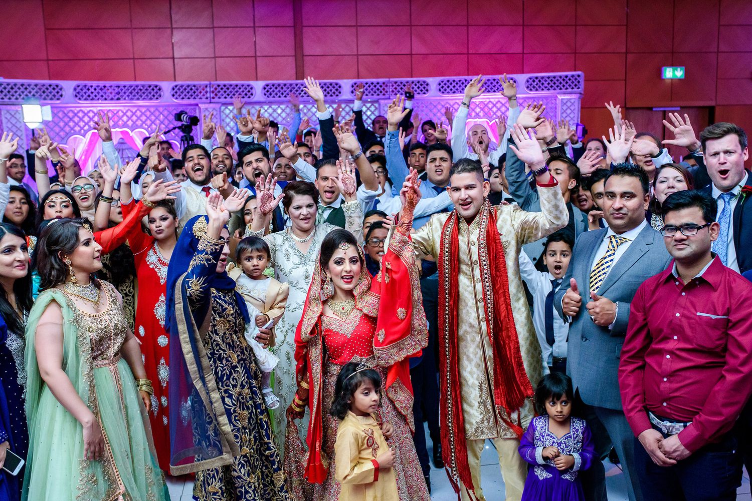 Large wedding reception gathering with guests in colorful traditional Indian attire.