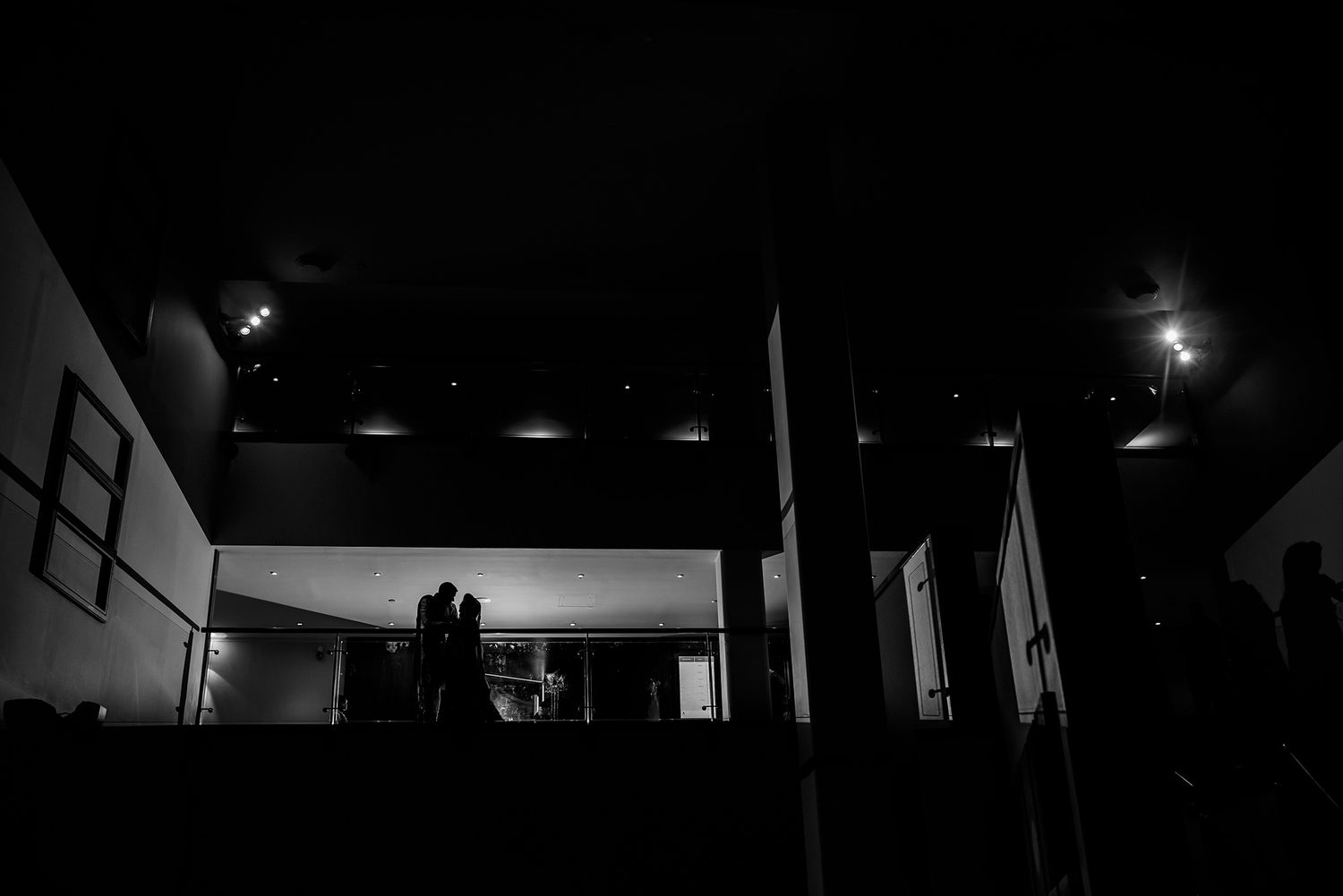 Dramatic black and white silhouettes of wedding guests in an architectural setting.