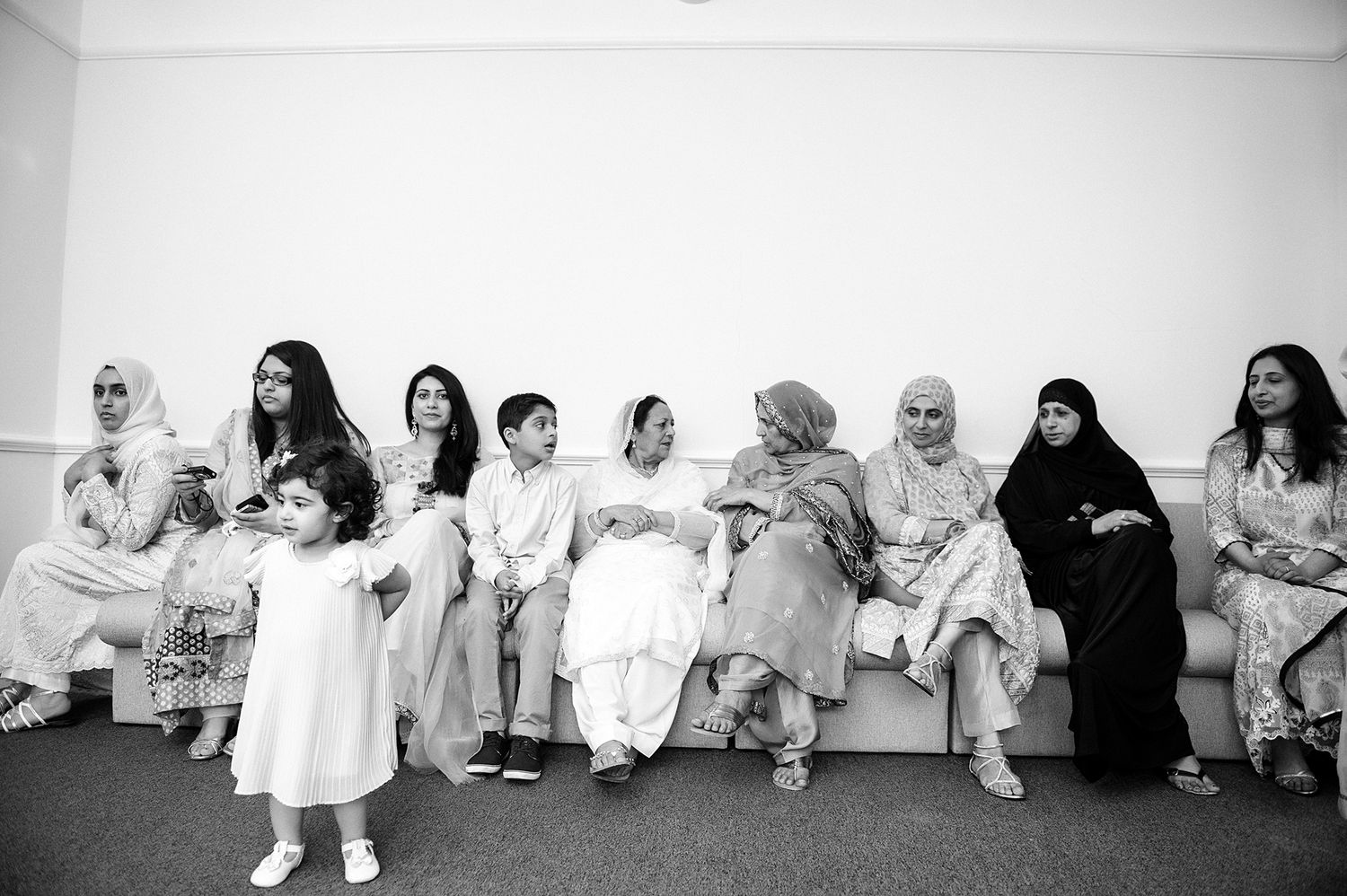 Black and white photo of women and children sitting together on a bench.