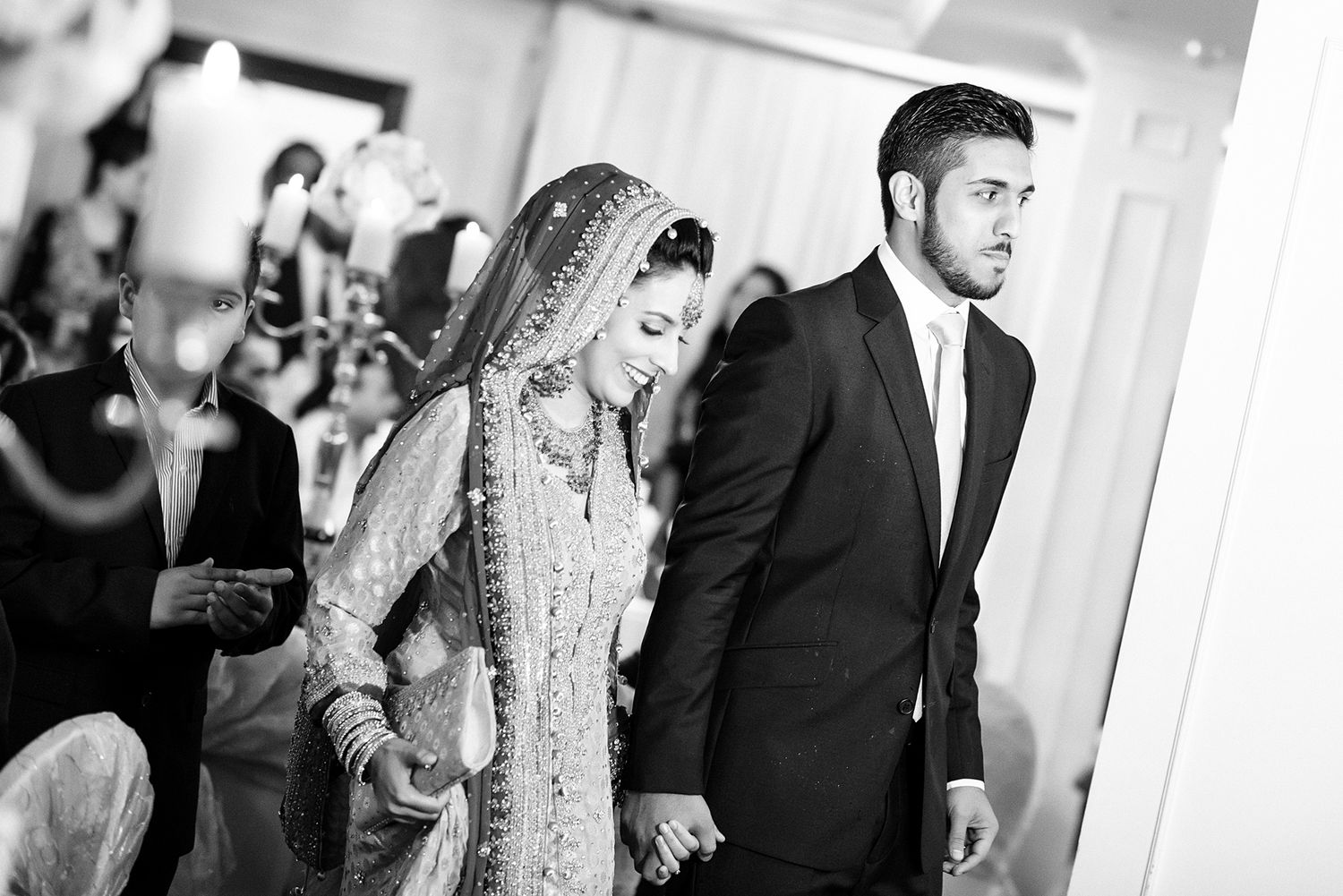 Wedding guests at a formal reception are shown interacting in black and white.