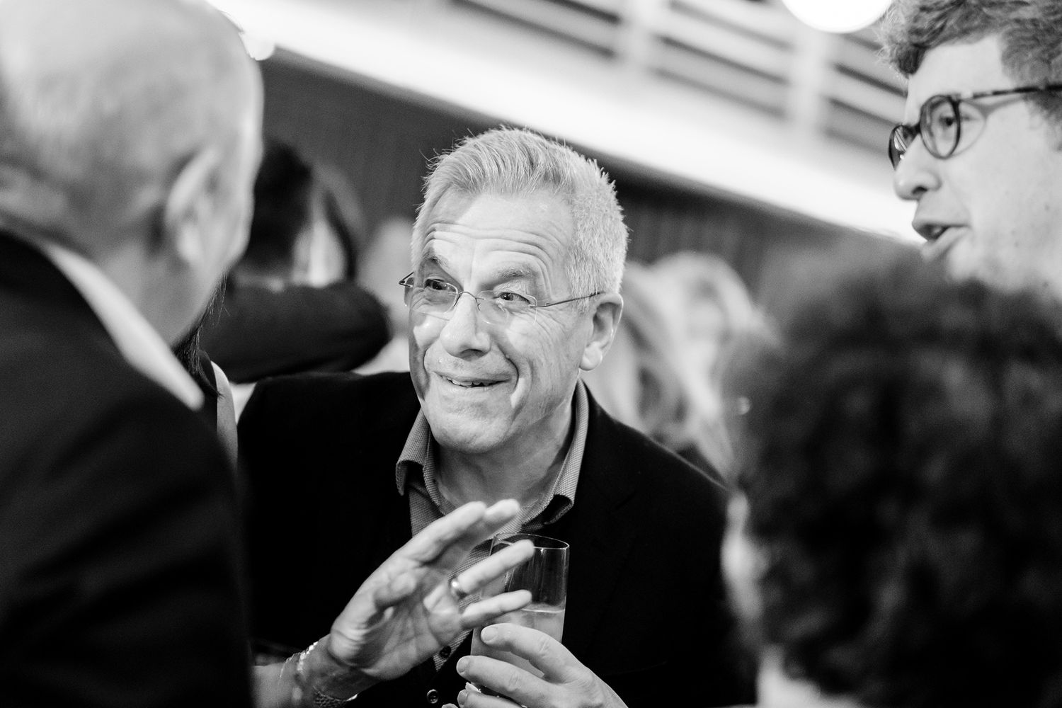 Black and white candid shots show attendees engaged in animated conversation at a formal event.