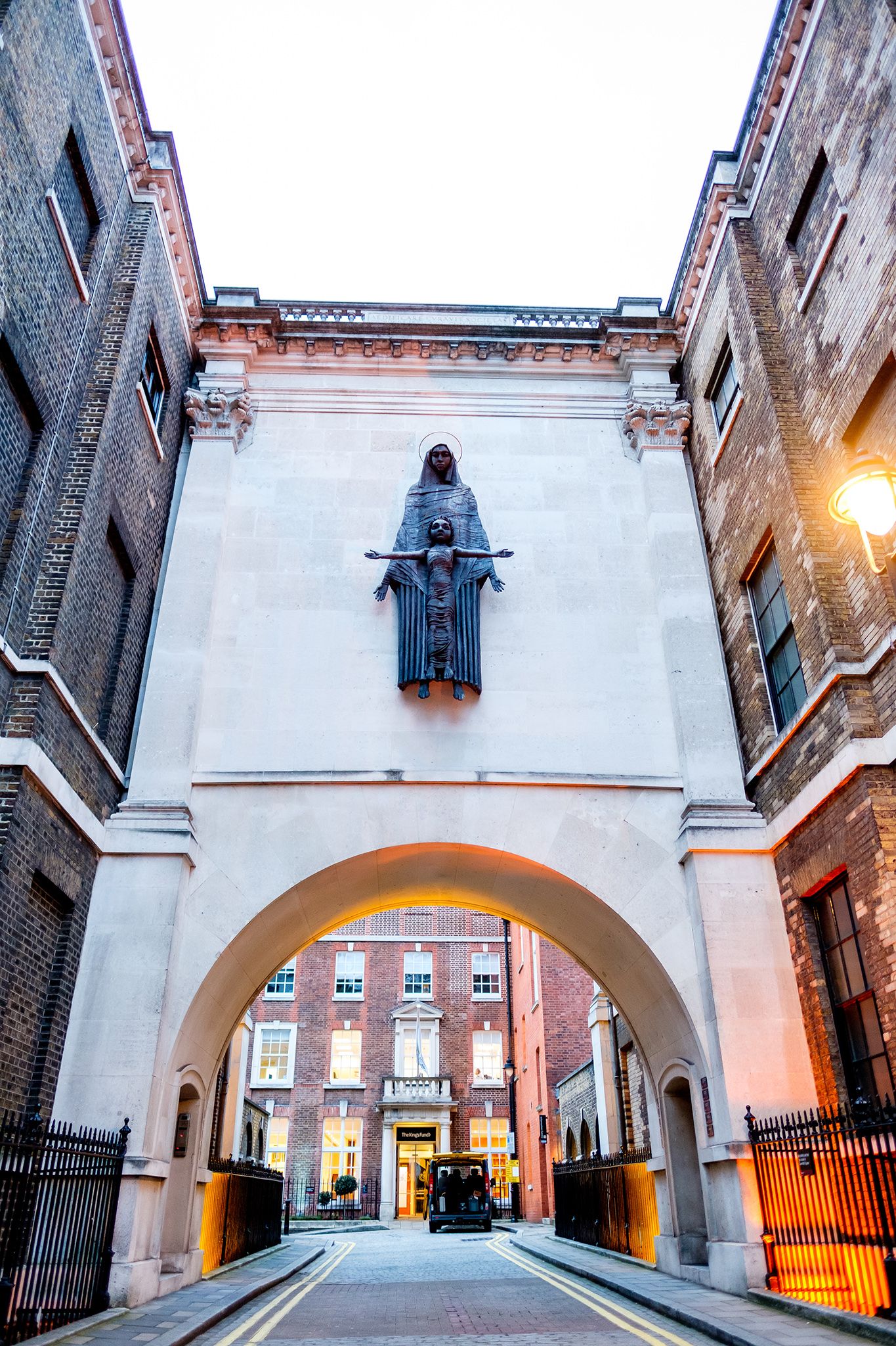 Architectural detail of an arched passageway between brick buildings with dramatic lighting.