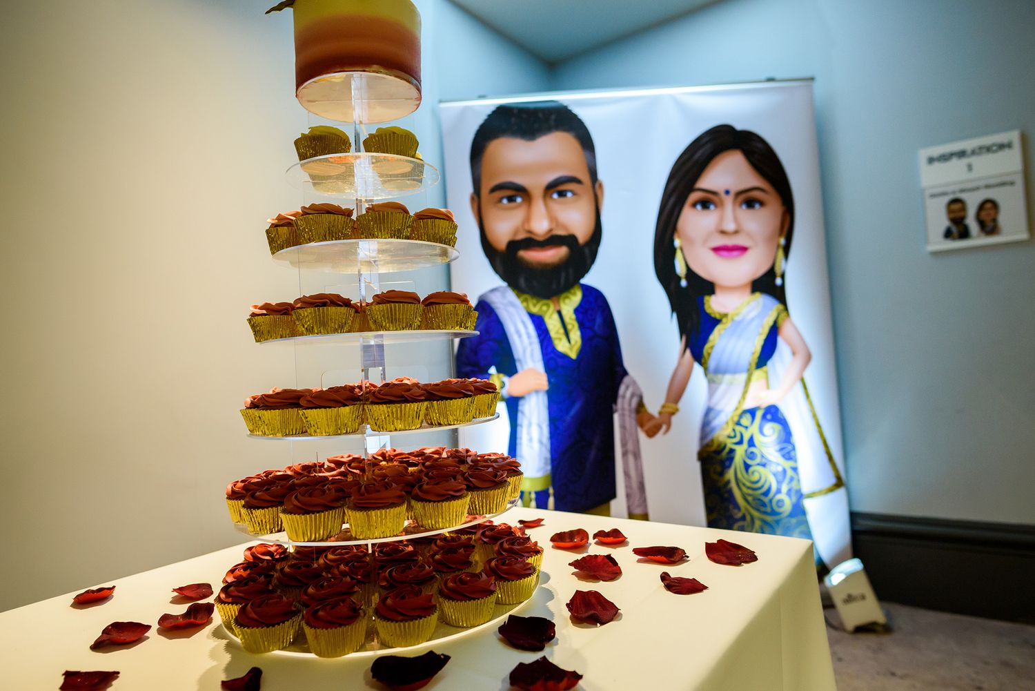 Unique wedding cake display with custom cartoon character cutouts beside a tiered dessert tower.