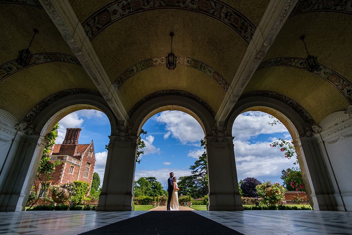 Historic stone colonnade with arched openings framing a bright blue sky.
