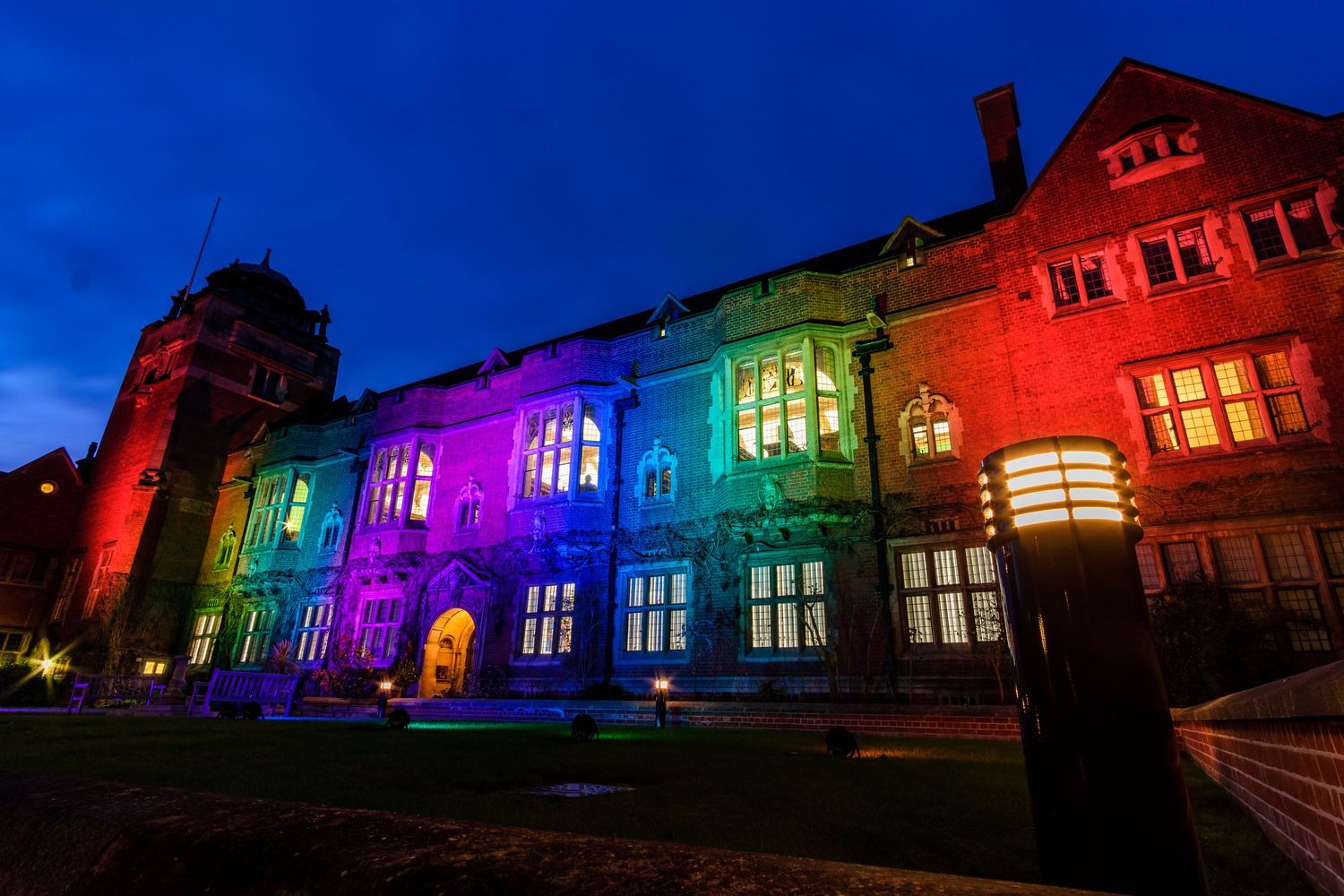 Historic building illuminated in vibrant rainbow colors against deep blue night sky.