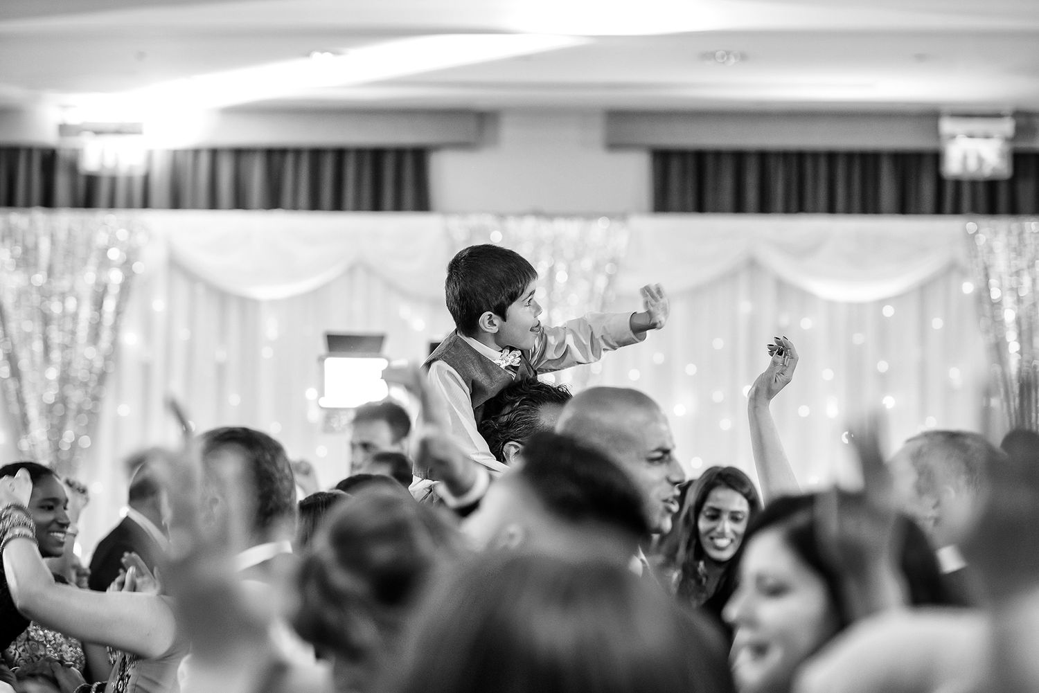Black and white photo of wedding guests celebrating on a crowded dance floor.