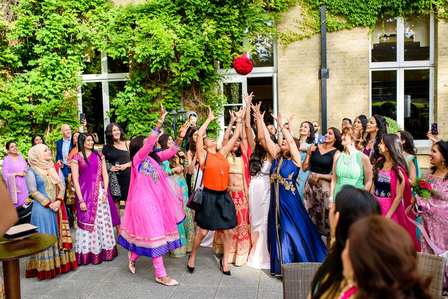 Celebratory group gathering with vibrant outfits in front of a yellow building.