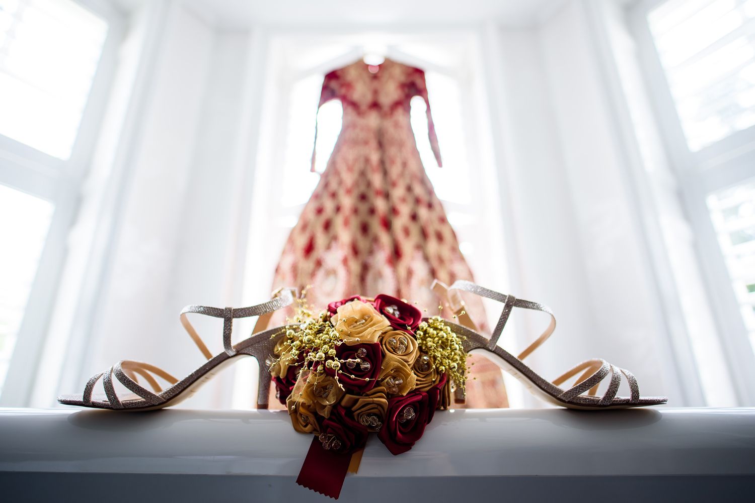 Elegant bridal accessories including high heel shoes and jewelry arranged by window.