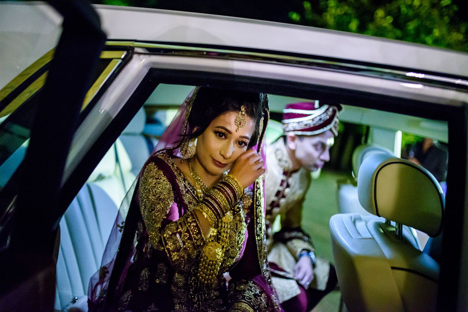 Traditional wedding attire and jewelry viewed through a car window.