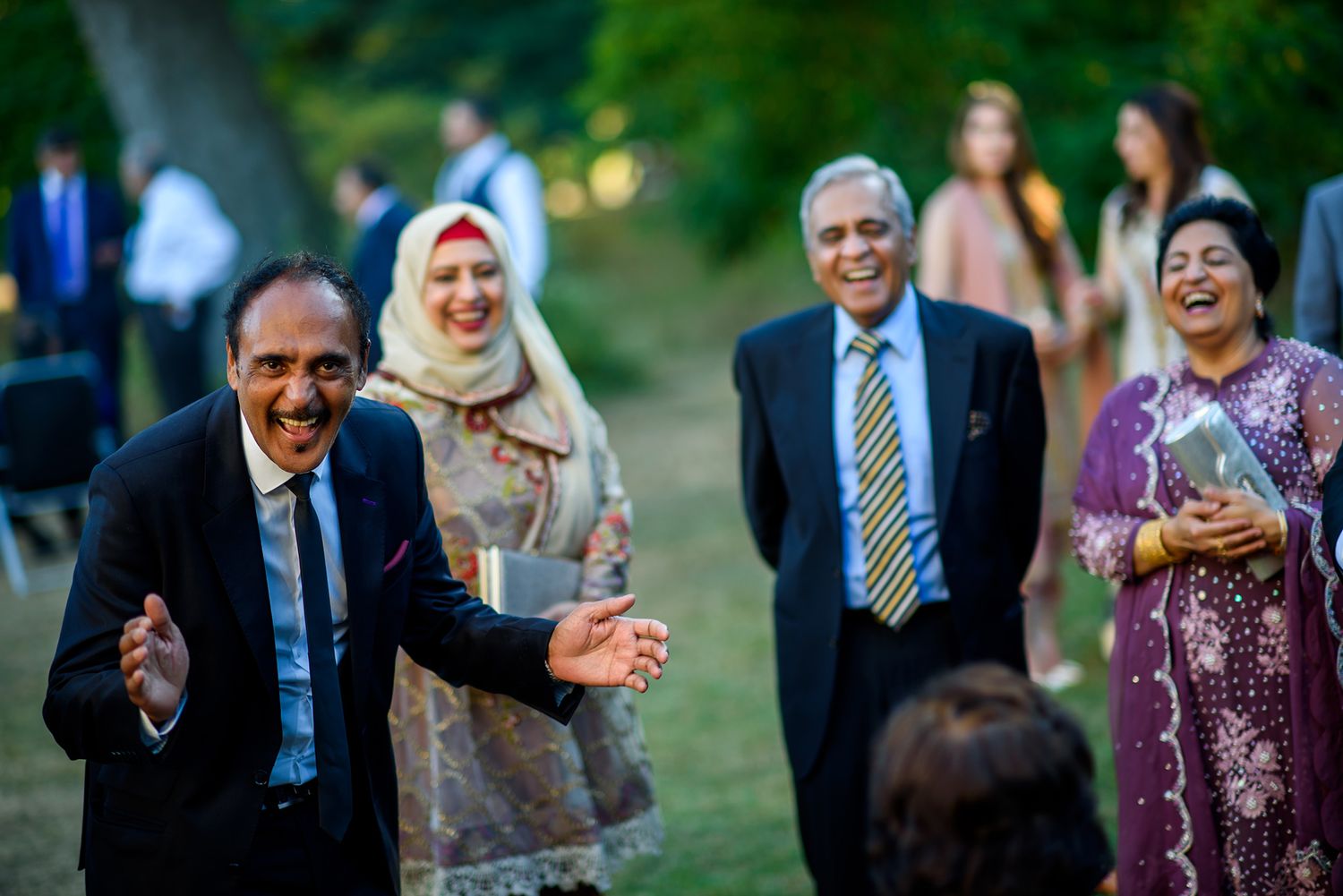 Wedding guests mingle and laugh together during an outdoor reception celebration.