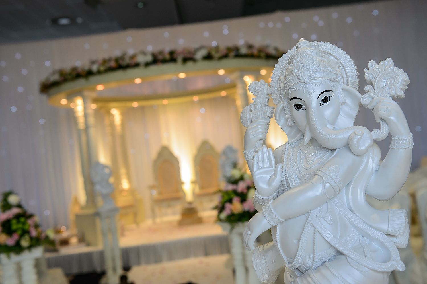 White decorative Ganesh statues and wedding decor elements against an elegant backdrop.