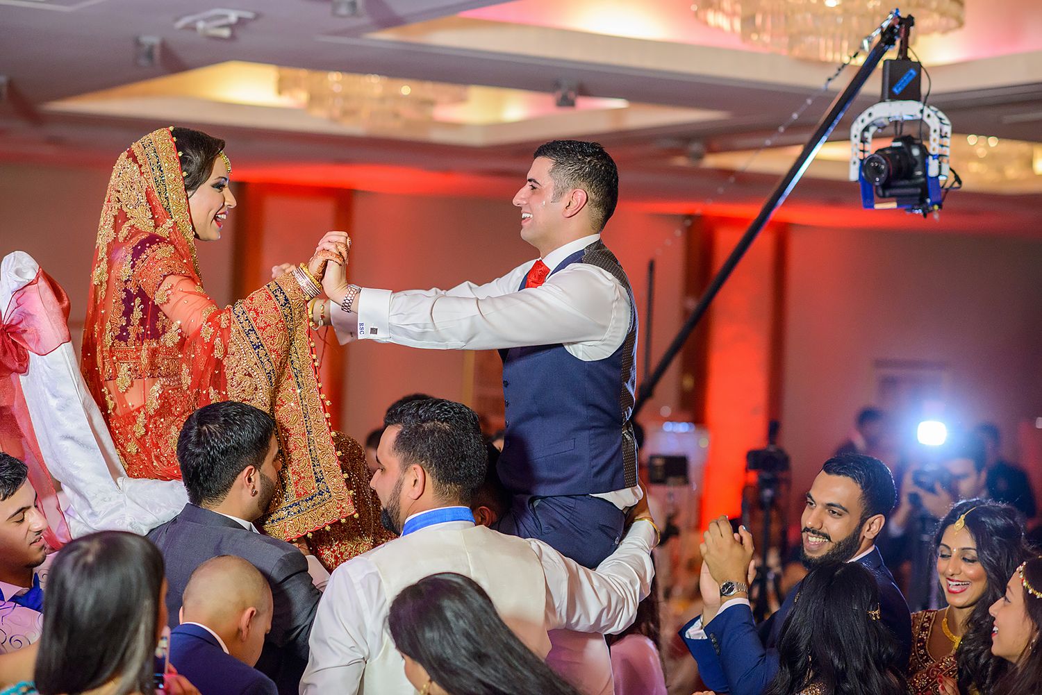 Wedding guests celebrating on a dance floor under red ambient lighting.
