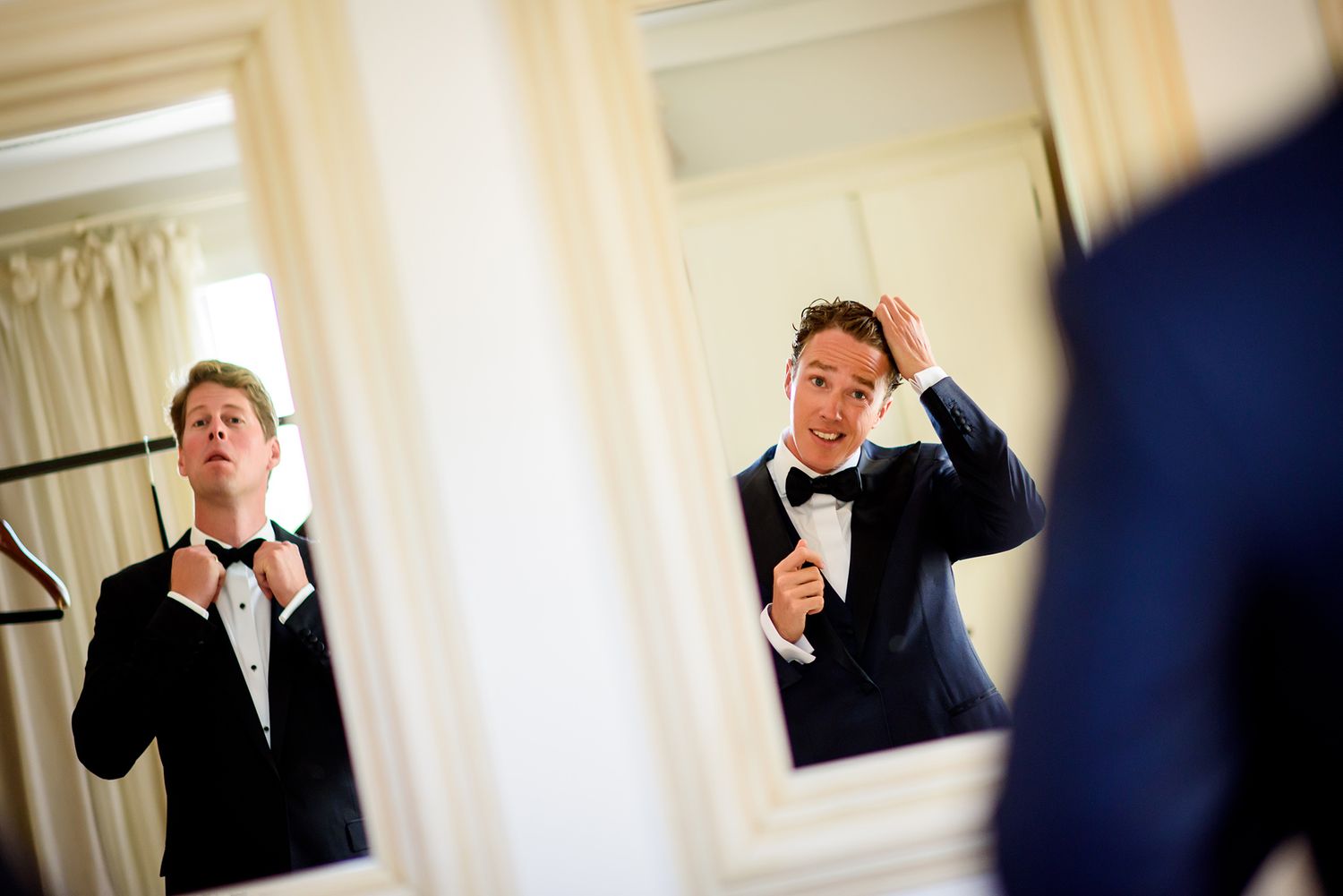 Men in formal attire prepare for an event in an elegant white room.