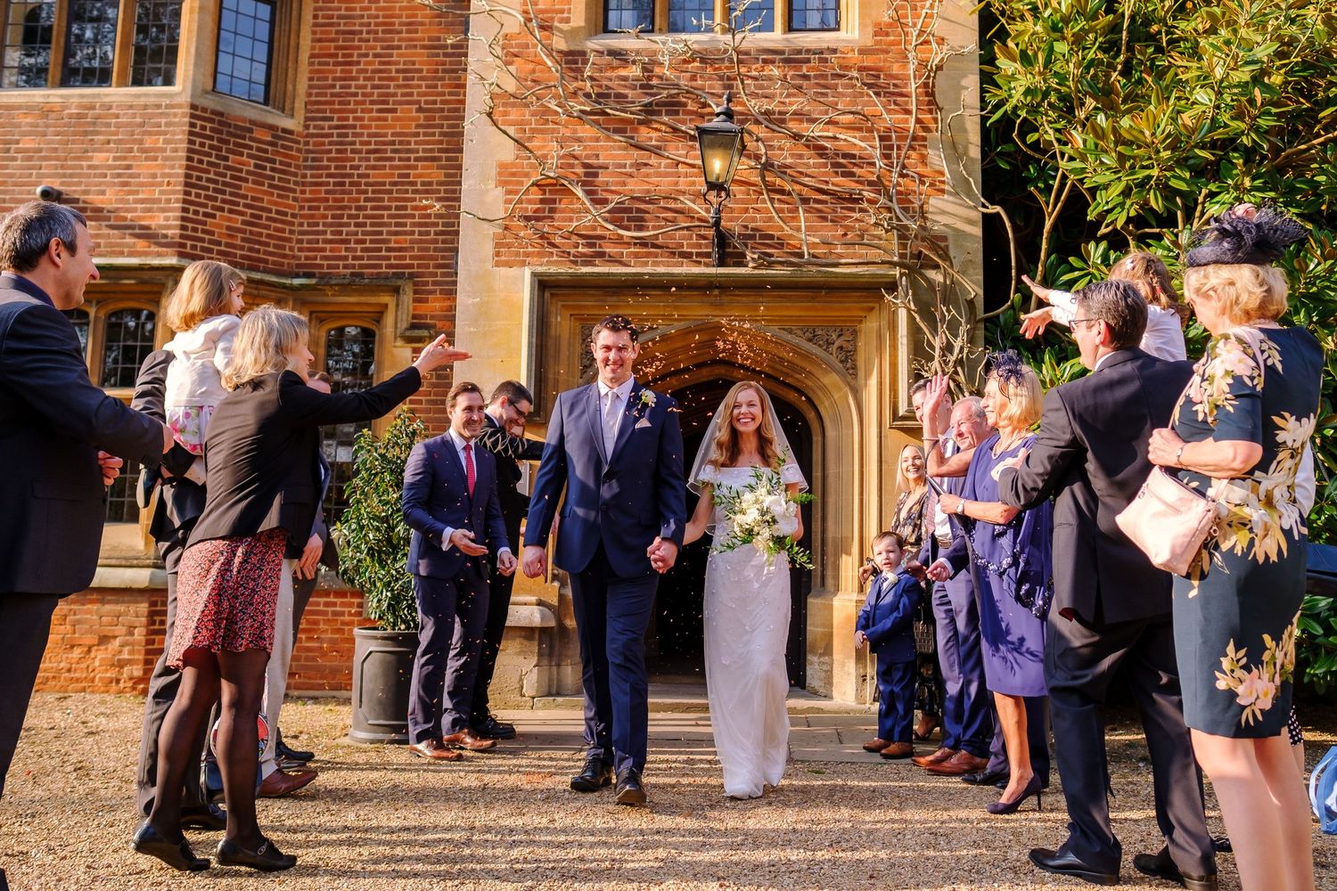 Wedding party lined up outside historic brick building during outdoor celebration.