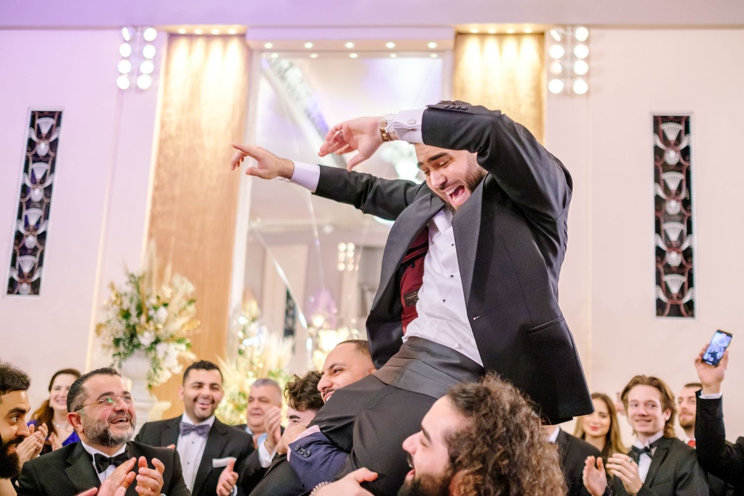 Wedding reception celebration with guests dancing and waving sparklers in a grand ballroom.