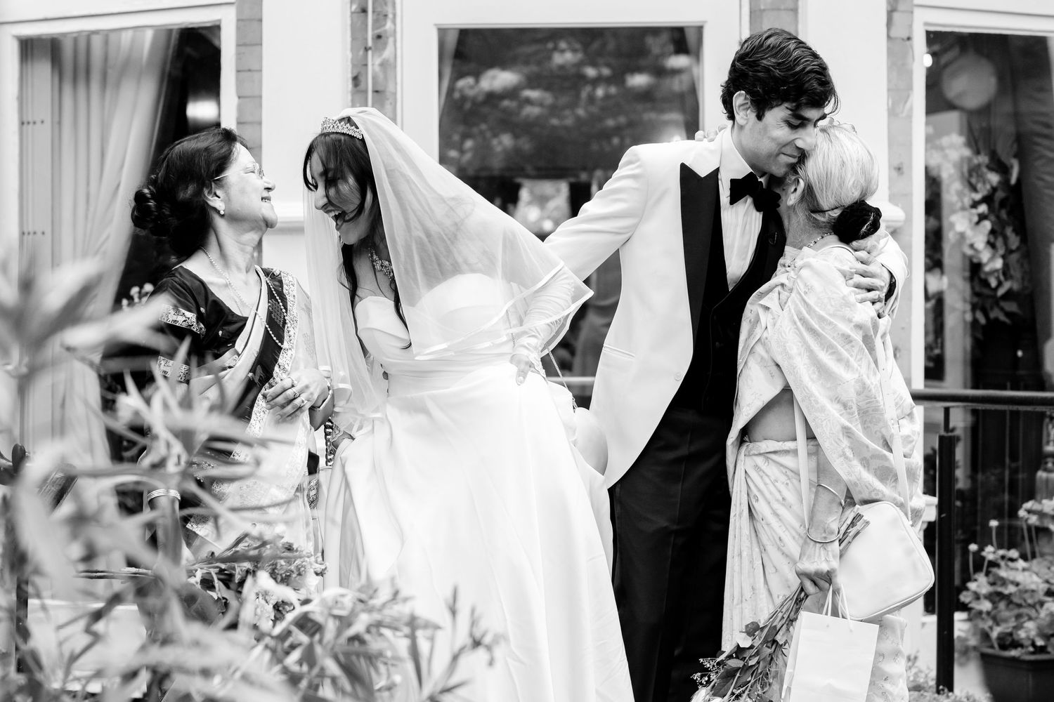 Black and white candid wedding photo showing joyful celebration in a garden setting.