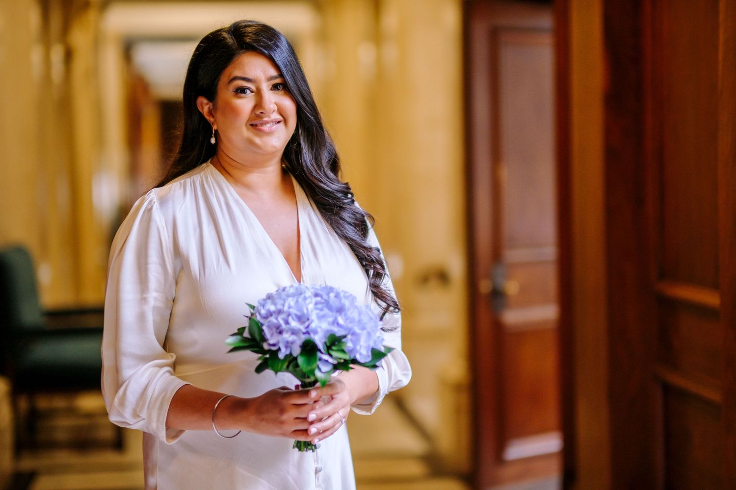 A bridal party getting ready in a warmly lit room with white robes and floral arrangements.