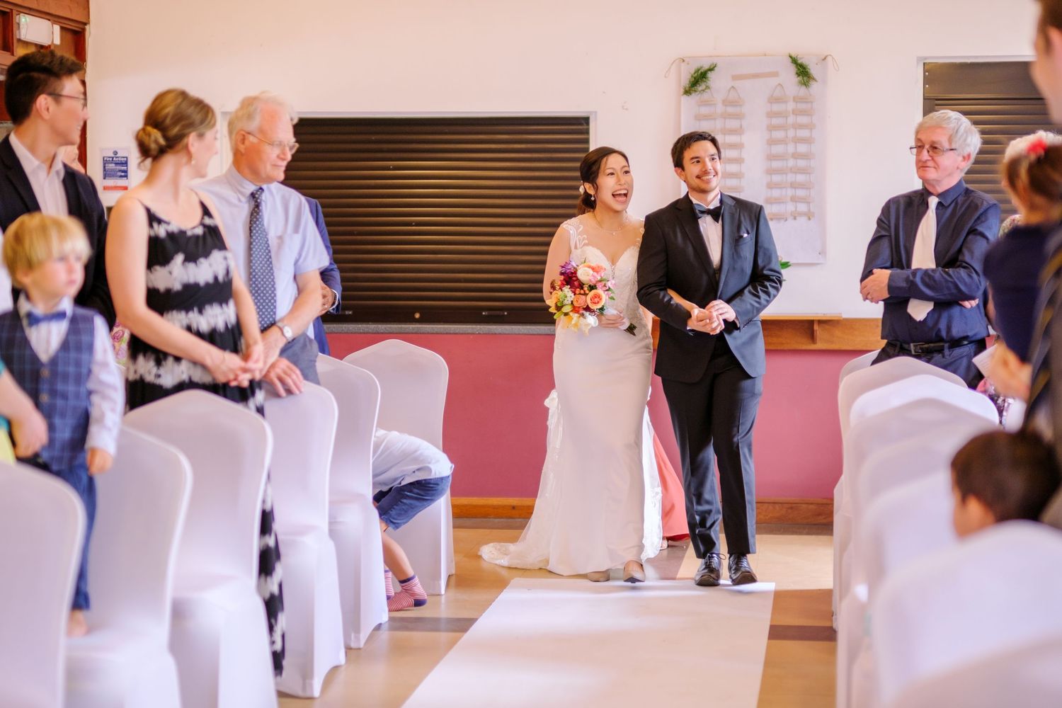 Wedding ceremony setup with white chair covers in a banquet hall.