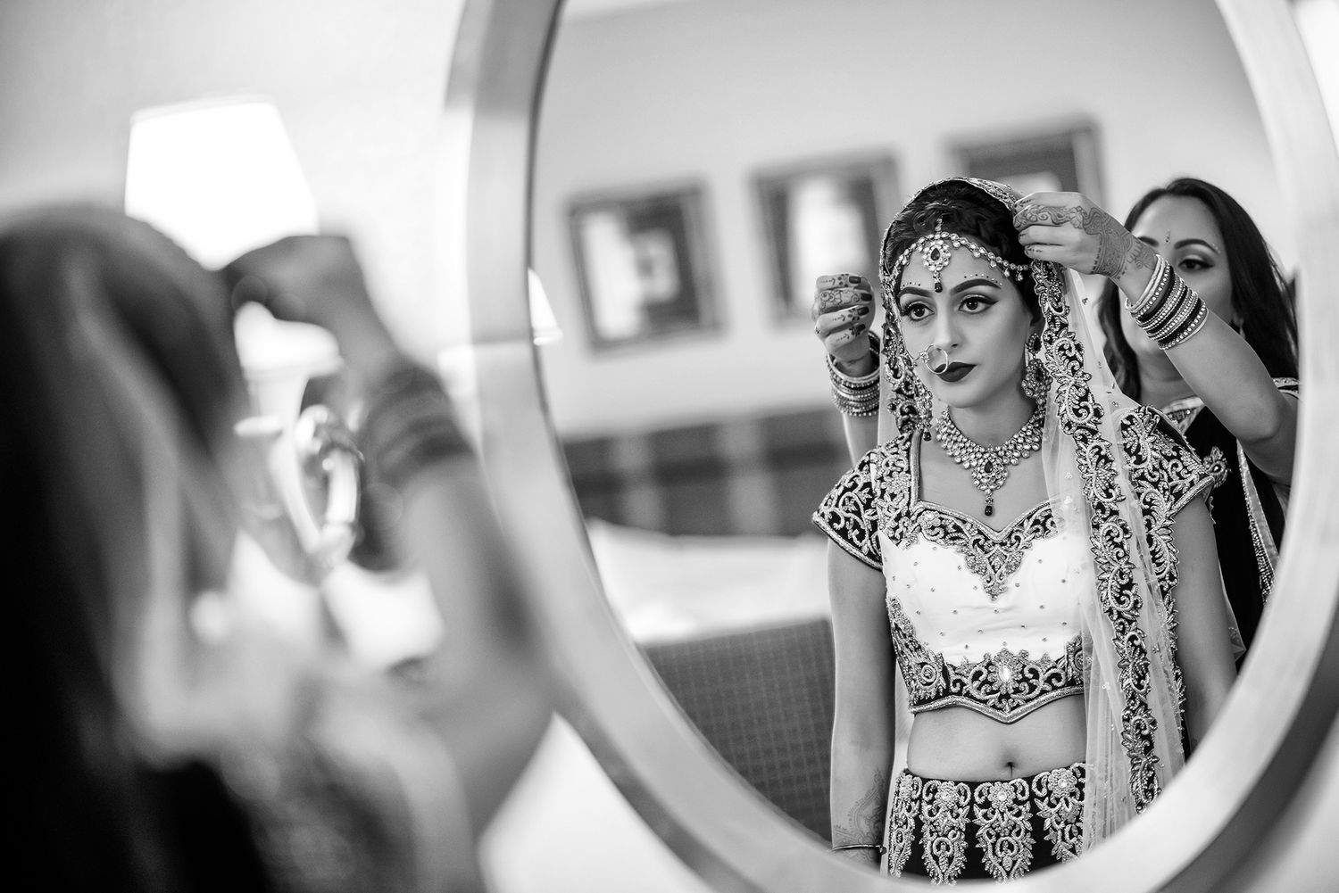 Black and white mirror reflection showing traditional Indian bridal preparations.