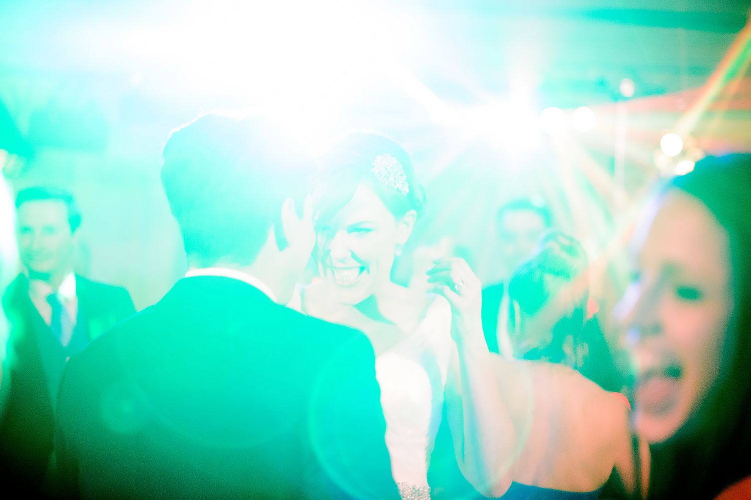 Wedding dance party with colorful turquoise lighting and people dancing.
