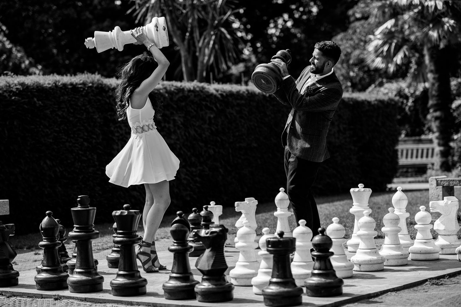 A playful moment captured on a giant outdoor chess board in black and white photography.