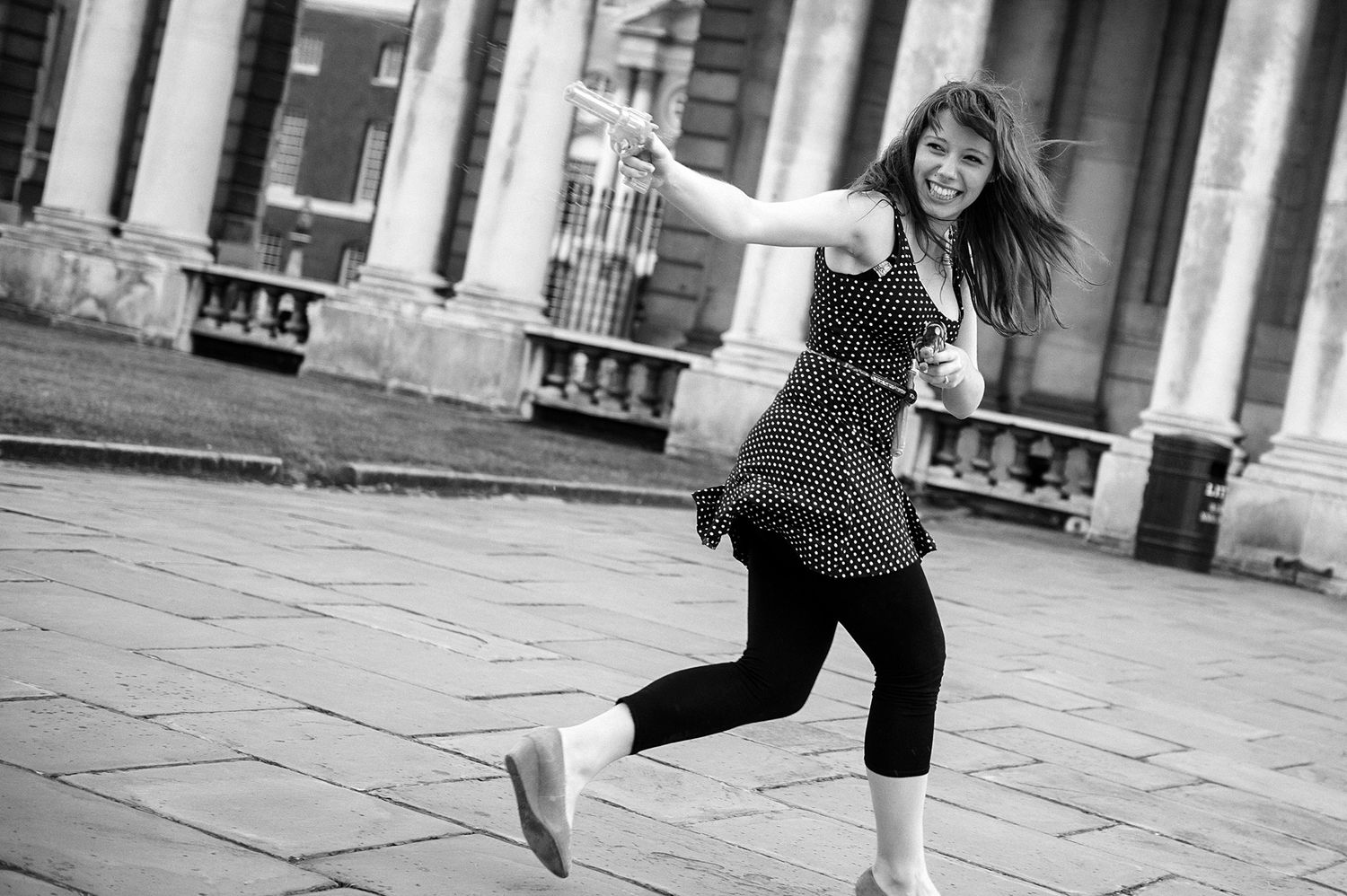 Person dancing and leaping joyfully in front of classical architecture.