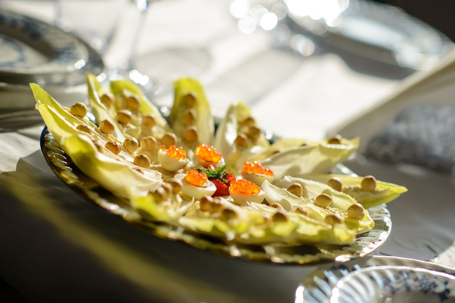 Elegant plated appetizers featuring garnished lettuce cups with colorful toppings on curved serving dishes.