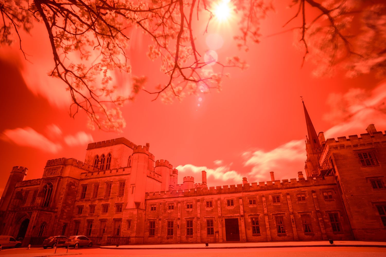 Historic building exterior photographed through tree branches with dramatic red-tinted sky.