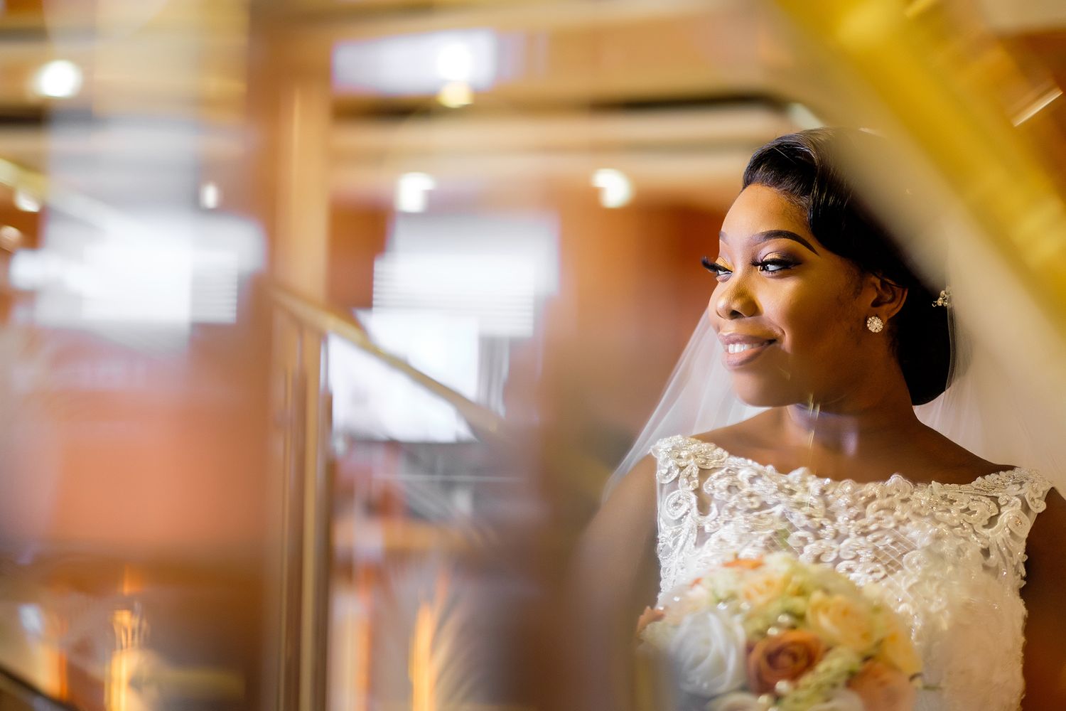 Close up portrait of bride with lace dress holding floral bouquet.