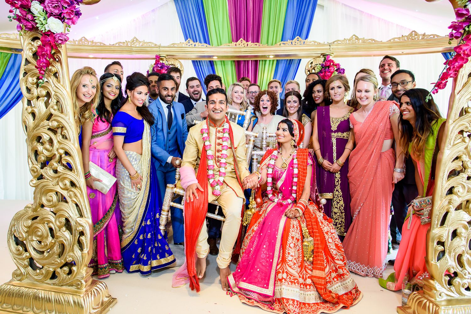 Traditional Indian wedding hall with vibrant pink and blue fabric draping and ornate gold decorations.
