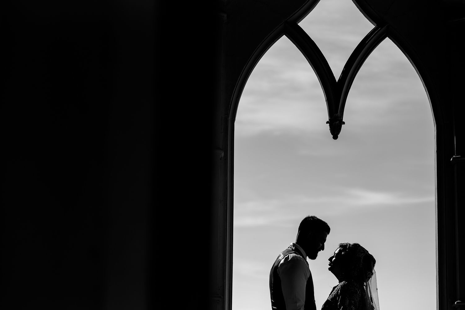 Figures silhouetted in Gothic church archway creating romantic atmosphere.