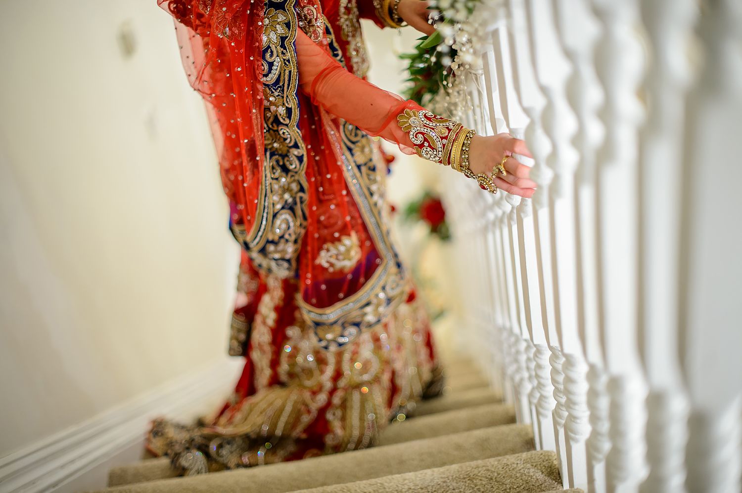 Ornate bridal details on white staircase with elegant red and gold attire.